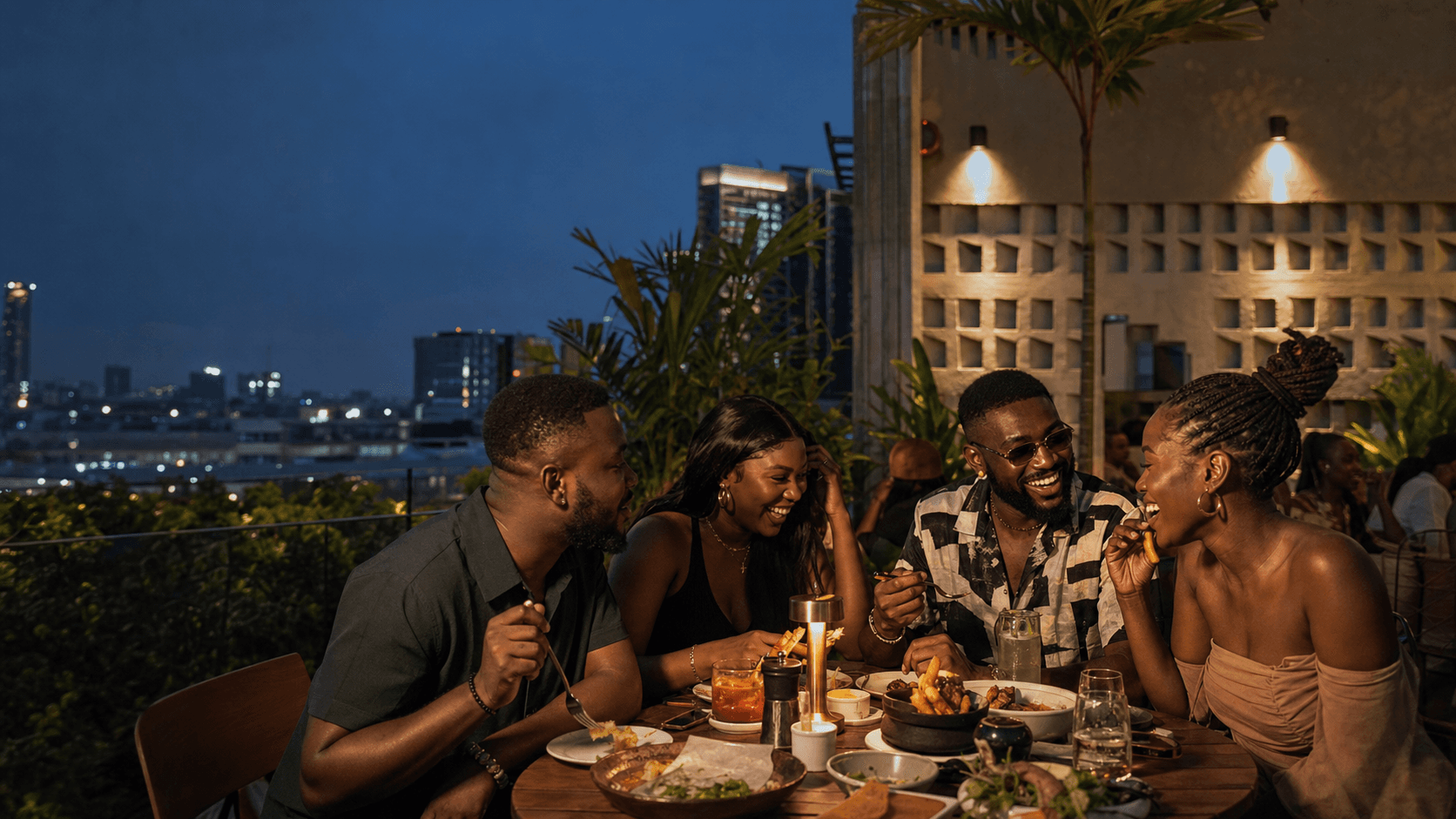Friends sharing food and laughing at a Lagos rooftop hangout